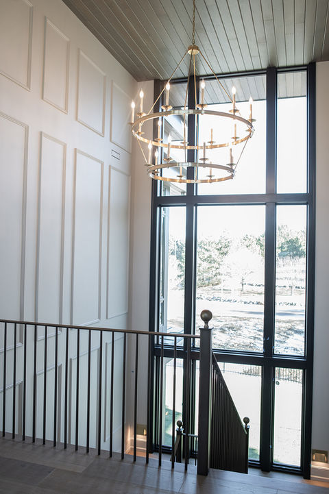 Stairway with Chandelier and Wall Paneling by Laura Lien Interior Design