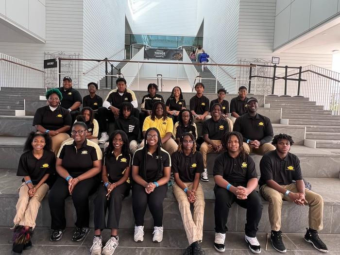 Success Academy students seated together on concrete bleachers indoors.