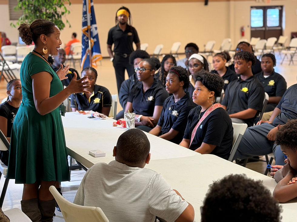 A speaker addressing a room of students in 100 Black Men chapter polo shirts
