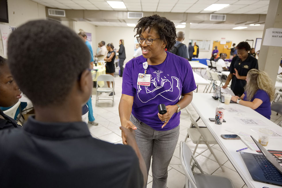 A young attendee speaks with a woman in purple at a summit resource table