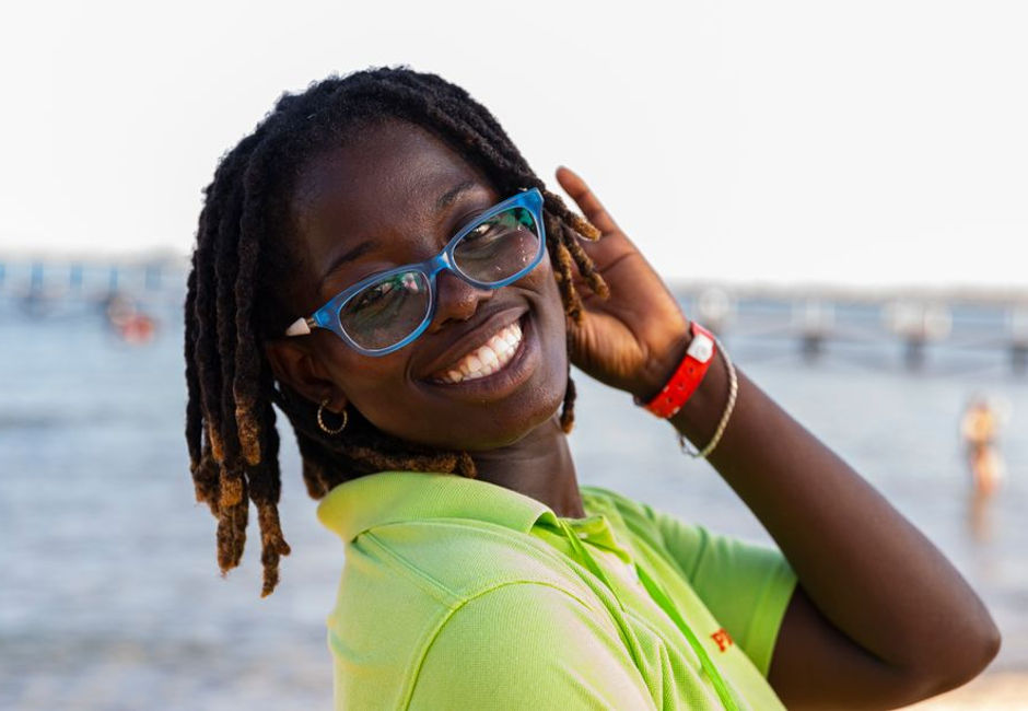 A person wearing sunglasses on a sunny day by the beach.