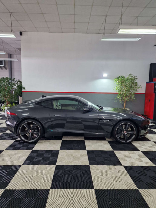 Dunkelgraues Sportwagen-Seitenprofil auf einem Schachbrettboden, innen Reinigung, Dr. Garage.