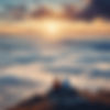 Two people meditating outdoors at the top of a mountain with a view of the clouds and a su