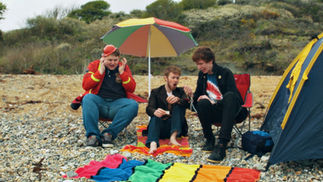 Brian the Fireman, Ed Sheeran and Zipwaz Humphries (Victor Hampson) panic at the results of a mood ring, while sat under a colourful parasol on a beach