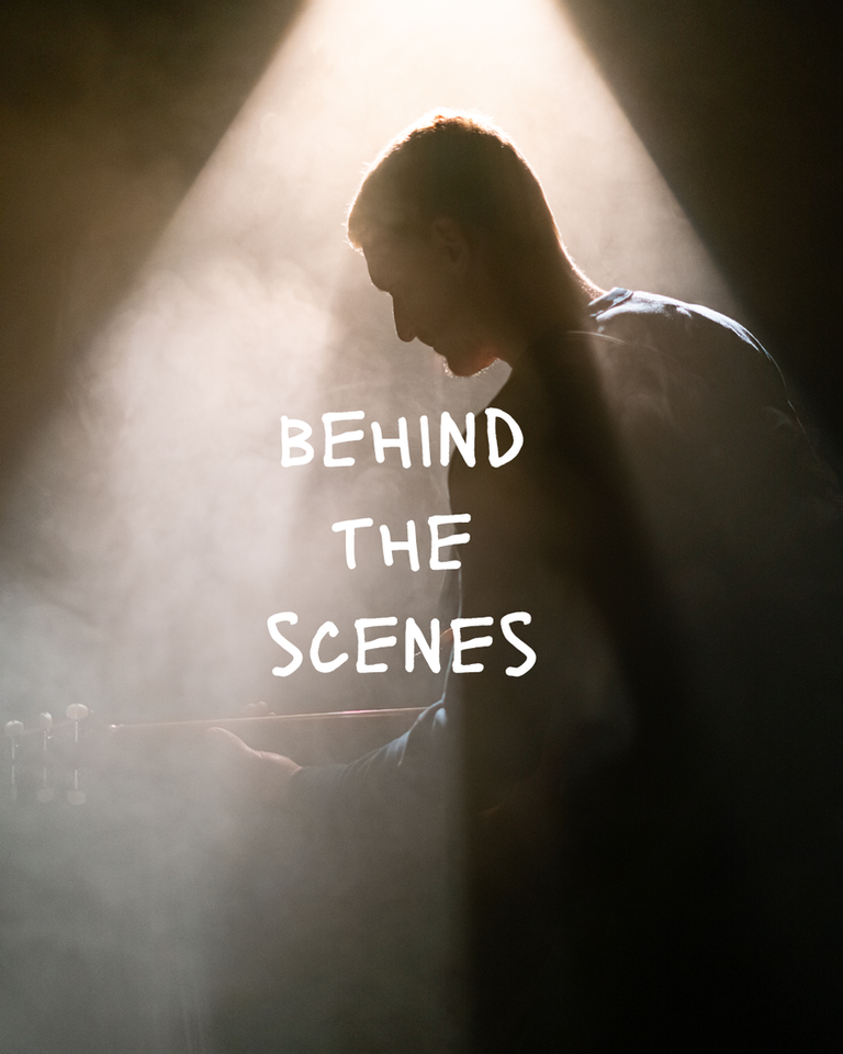 Ein Gitarrist steht in einem Lichtkegel und Nebel, auf dem Bild ist der Schriftzug "Behind the scenes" zu sehen