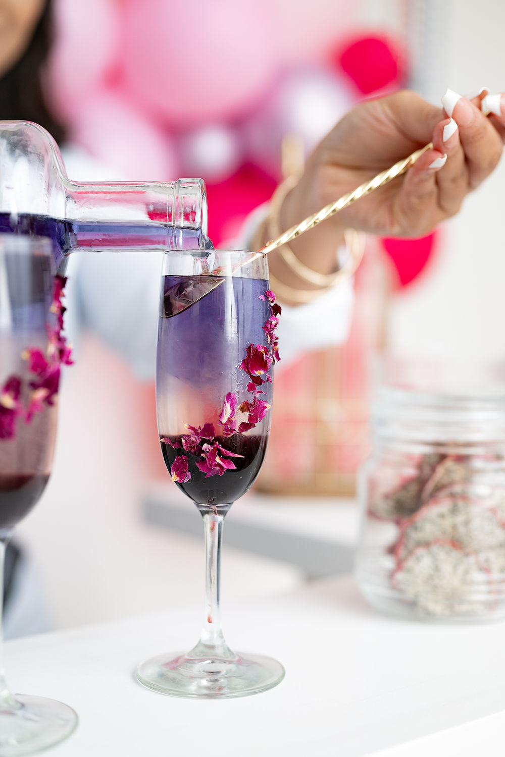 Pouring purple cocktail with rose petals