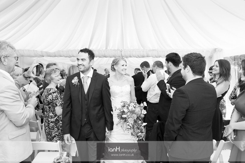 Bride and Groom smiling as they walk down the aisle