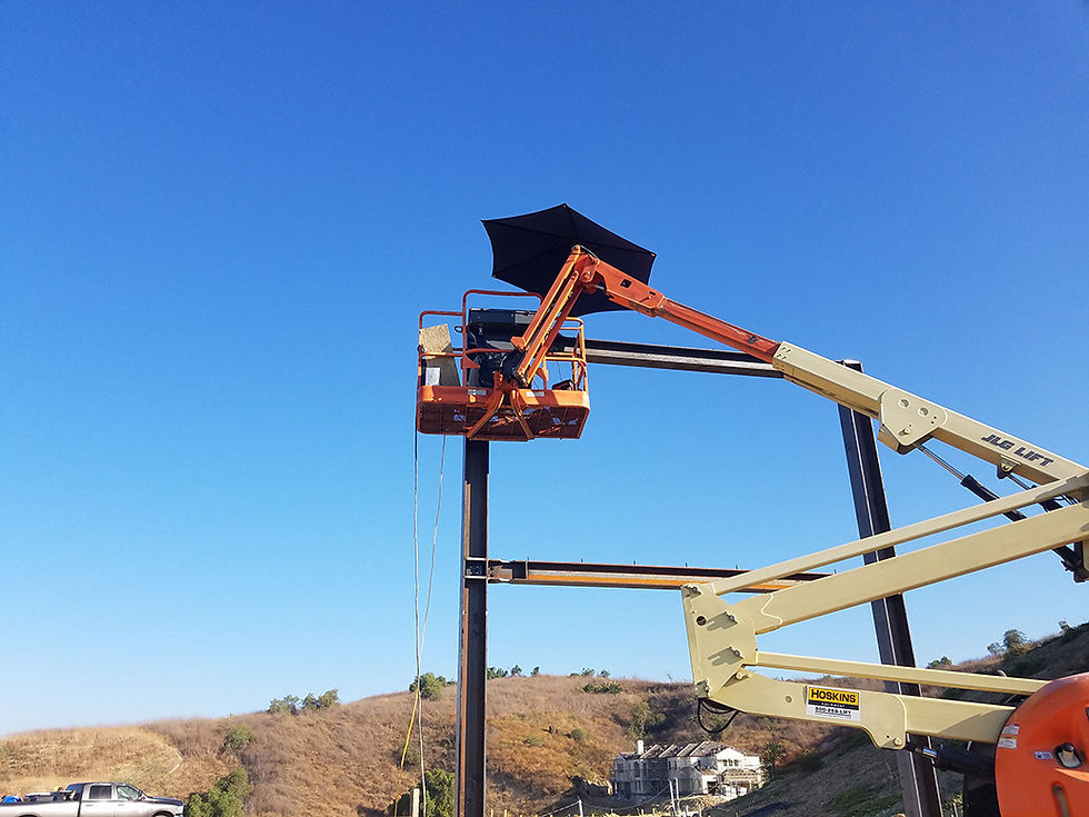Construction site lift hoists with an umbrella, setting beams against a clear blue sky.