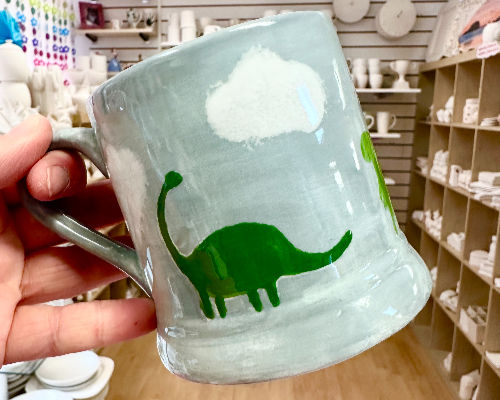 Mug painted with a dinosaur design  at crafty monkey pottery painting studio