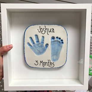 Baby hand and foot prints in clay framed in white frame and prints painted pale blue