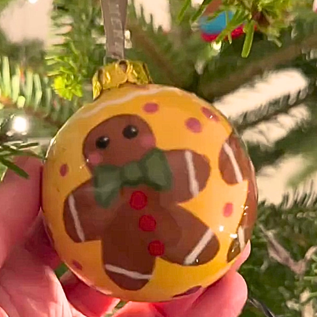 Bauble hanging on a Christmas tree, the bauble has a Gingerbread design painted on.