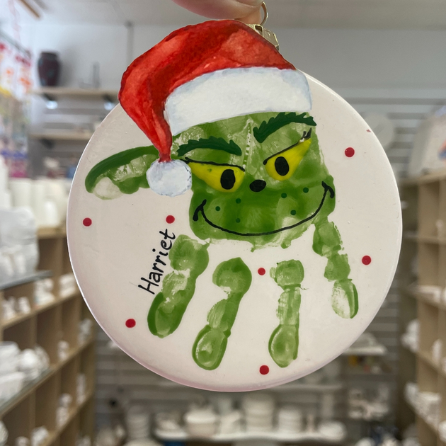 A baby handprint that has been painted to look like the Grinch.