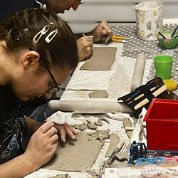 a customer adding stamps to a piece of clay