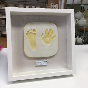 White framed clay impressions of babies hand and foot with prints painted yellow