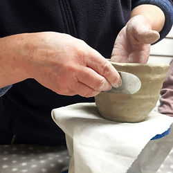 a person forming a bowl in clay