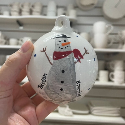 A baby footprint on a bauble that has been painted to look like a snowman.