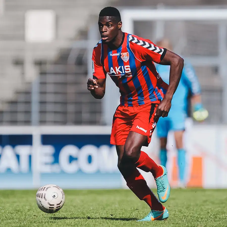 Kofi Schulz running with the ball in KFC Uerdingen 05’s red and blue striped kit.