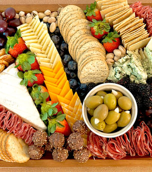Edible arrangements that include robust cheeses and meats with crackers, nuts and sweets.