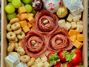 Edible arrangements that include robust cheeses and meats with crackers, nuts and sweets.