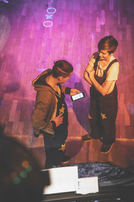 Zwei Personen betrachten ein Smartphone, Sterne auf der Kleidung, Blick von oben. Circus Radefiz.