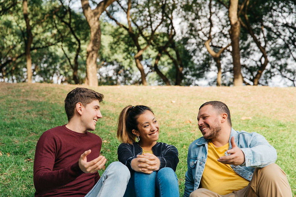Group of young adults talking together in a park, highlighting the importance of healthy relationships, peer support, and community during recovery