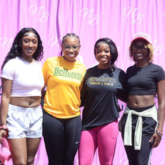 Four women smiling; pink banner behind them