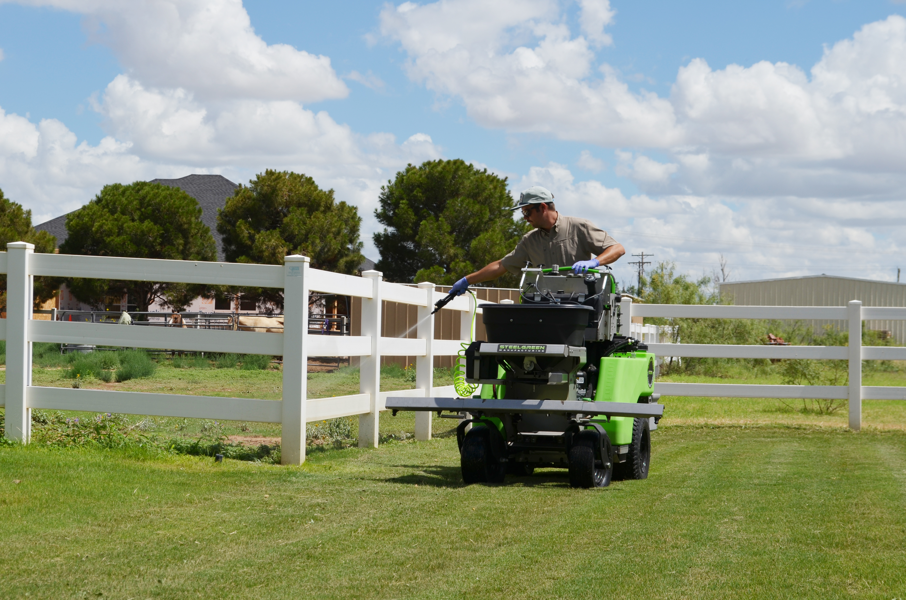 Tejas Pest and Weed Control tech on stand-on sprayer treating landscape near trees for Seminole TX fall tree care