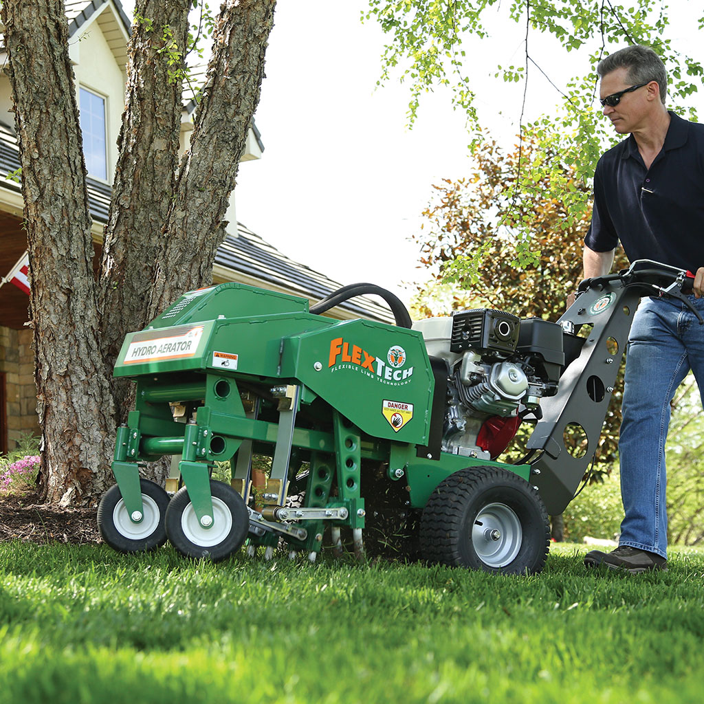 Tejas crew operating a Flextech hydro aerator on a residential lawn