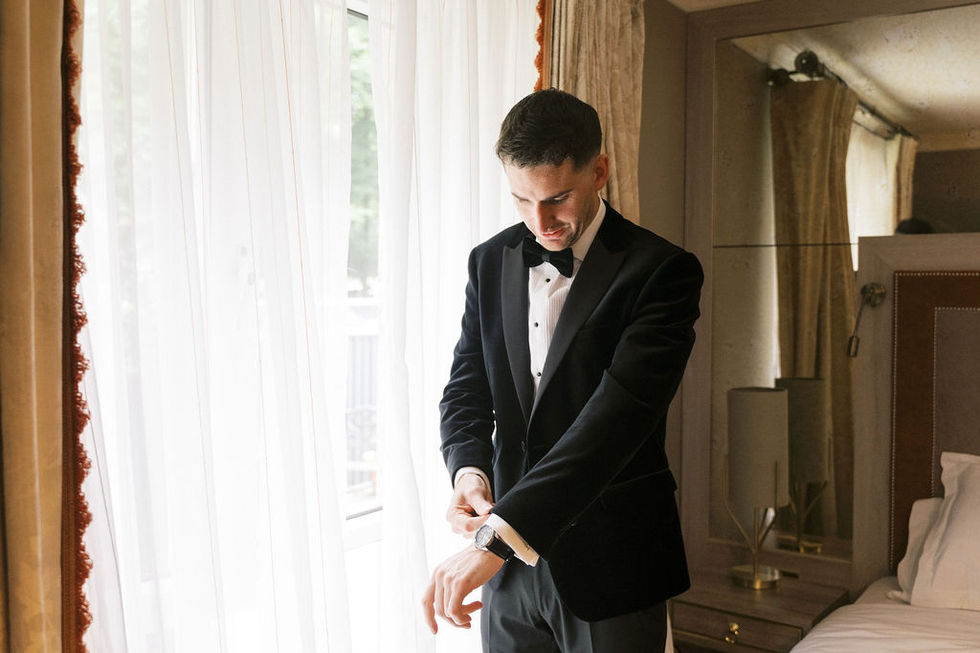 a man in a tuxedo adjusts his cufflinks