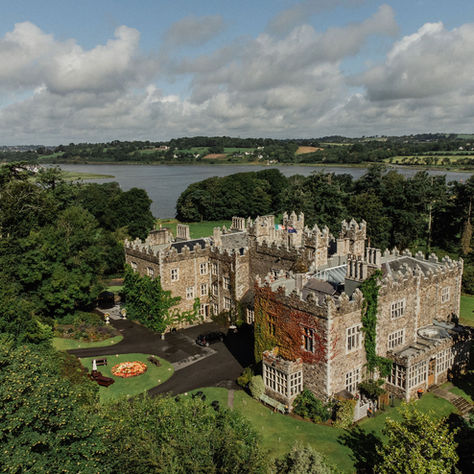 Elegant wedding couple portrait taken at Waterford Castle with lush greenery and historic castle backdrop.