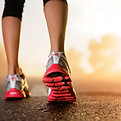 Runner feet running on road closeup on shoe woman fitness sunrise jog workout welness conc