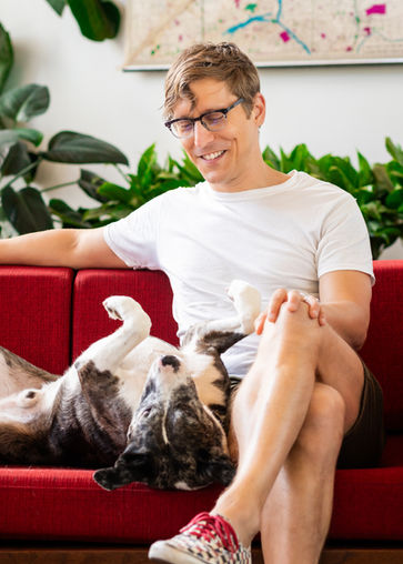 Man petting dog on red couch
