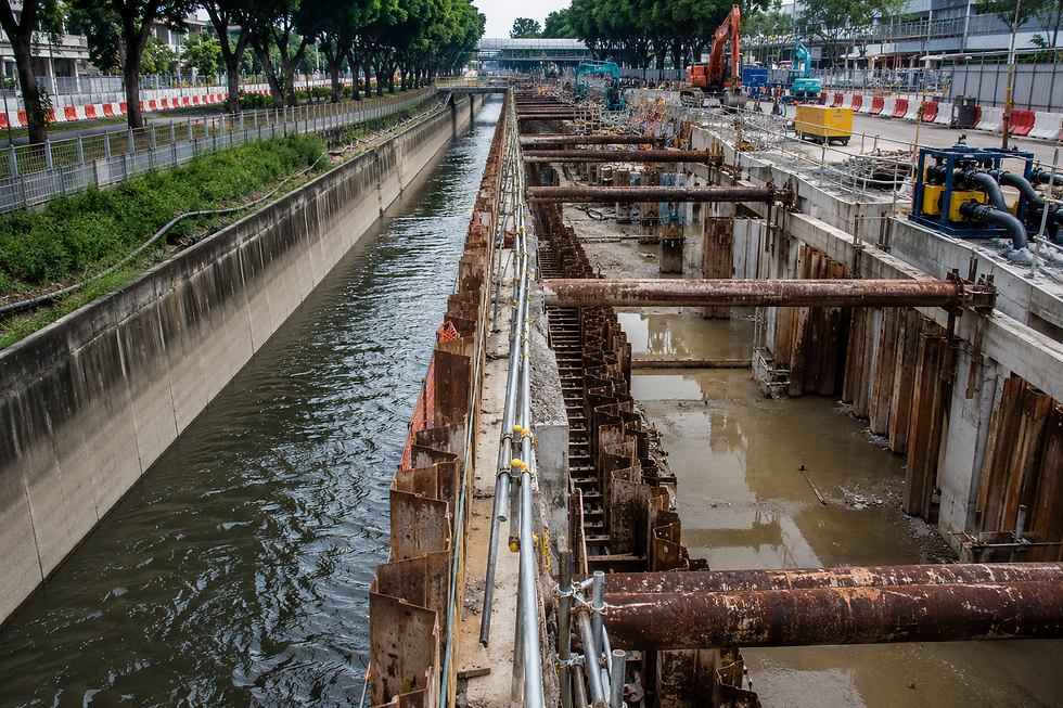 Drainage upgrading works in Singapore showing active construction beside an operational drainage canal carrying continuous water flow