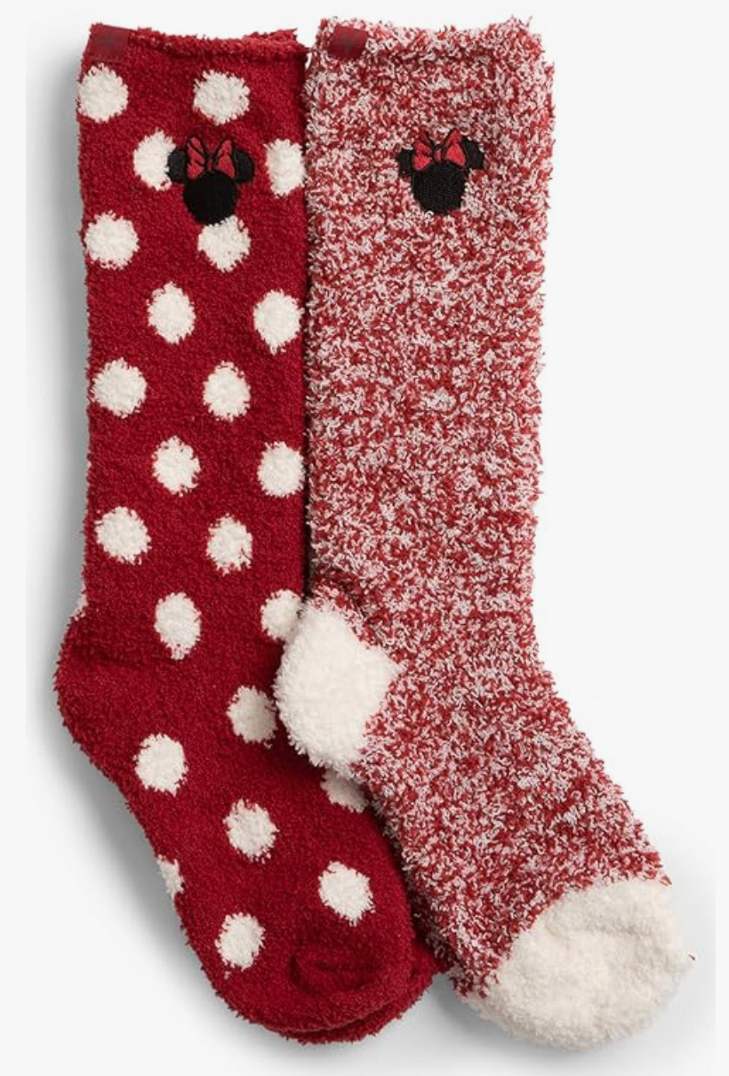 Red and white fuzzy socks; one with polka dots, the other marled. Both feature a black silhouette with a bow. Cozy and playful vibe.