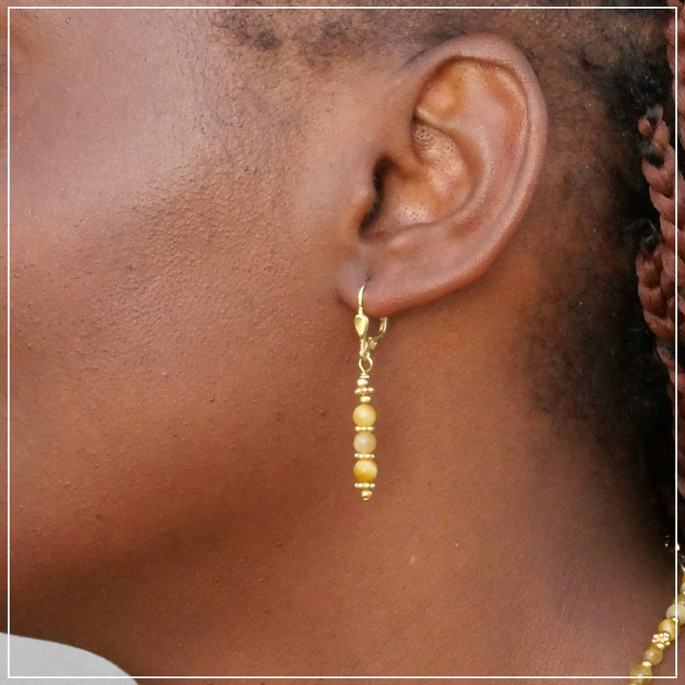 Gros plan sur les boucles d'oreilles Xénia en Oeil de Tigre, portées par un modèle