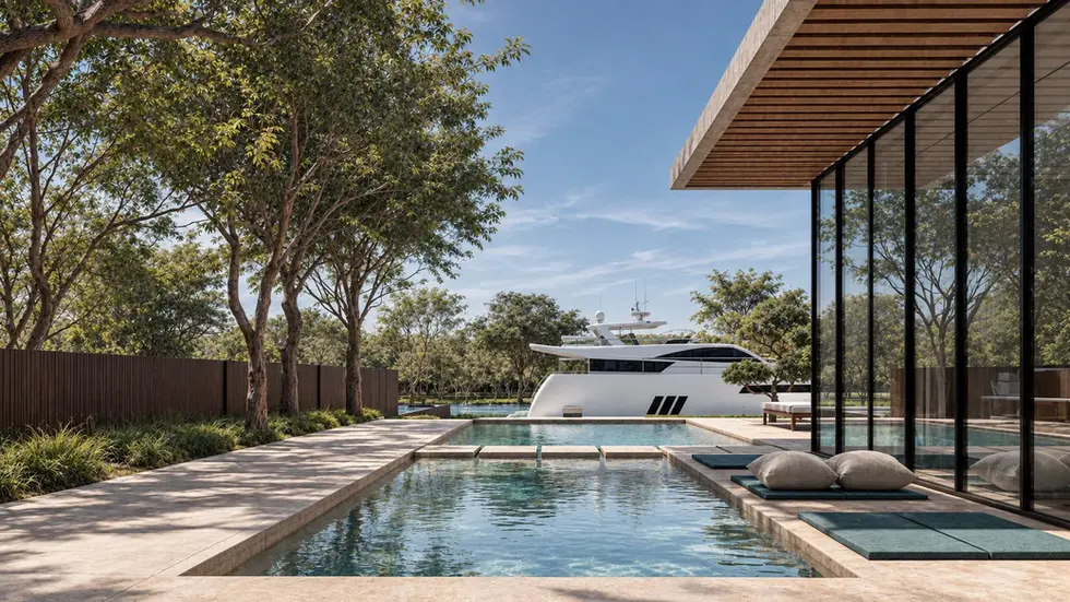 Tree-lined pool beside a glazed pavilion with timber eave, with a yacht moored at the waterfront beyond