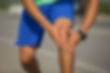 Runner holding their knee after experiencing an injury, Chiropractic Treatments at Parkway Back and Foot Clinic will help relieve and manage injury-related pain.