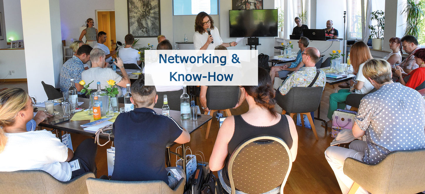 Rückansicht mehrerer
Seminarteilnehmer während eine Rednerin mit ihnen spricht.