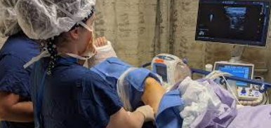 A woman scans a man's leg using an ultrasound machine