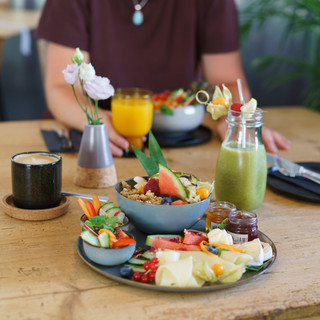Holztisch mit Frühstücksplatte und grünem Smoothie