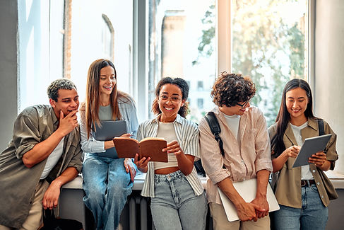 Five smiling diverse confident smart college students standing near window reading books a