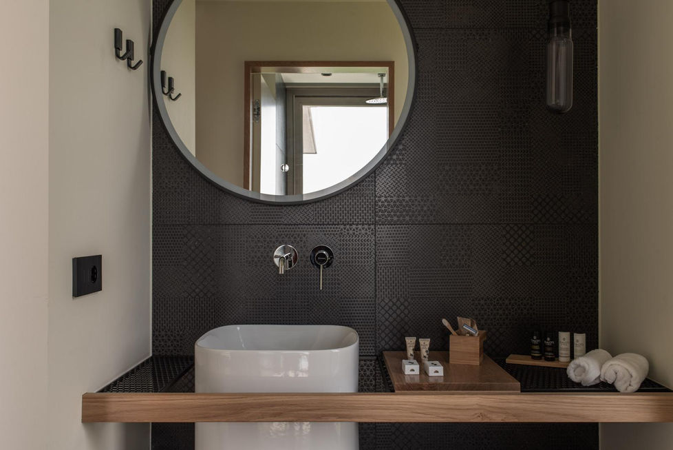 Salle de bains moderne dans une villa à Ammousso, avec un lavabo design et un miroir rond