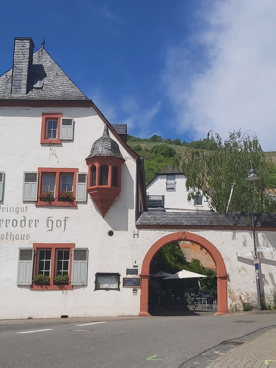 Ein Weingut an der Mosel mit Toreinfahrt. Dahinter Weinberge.