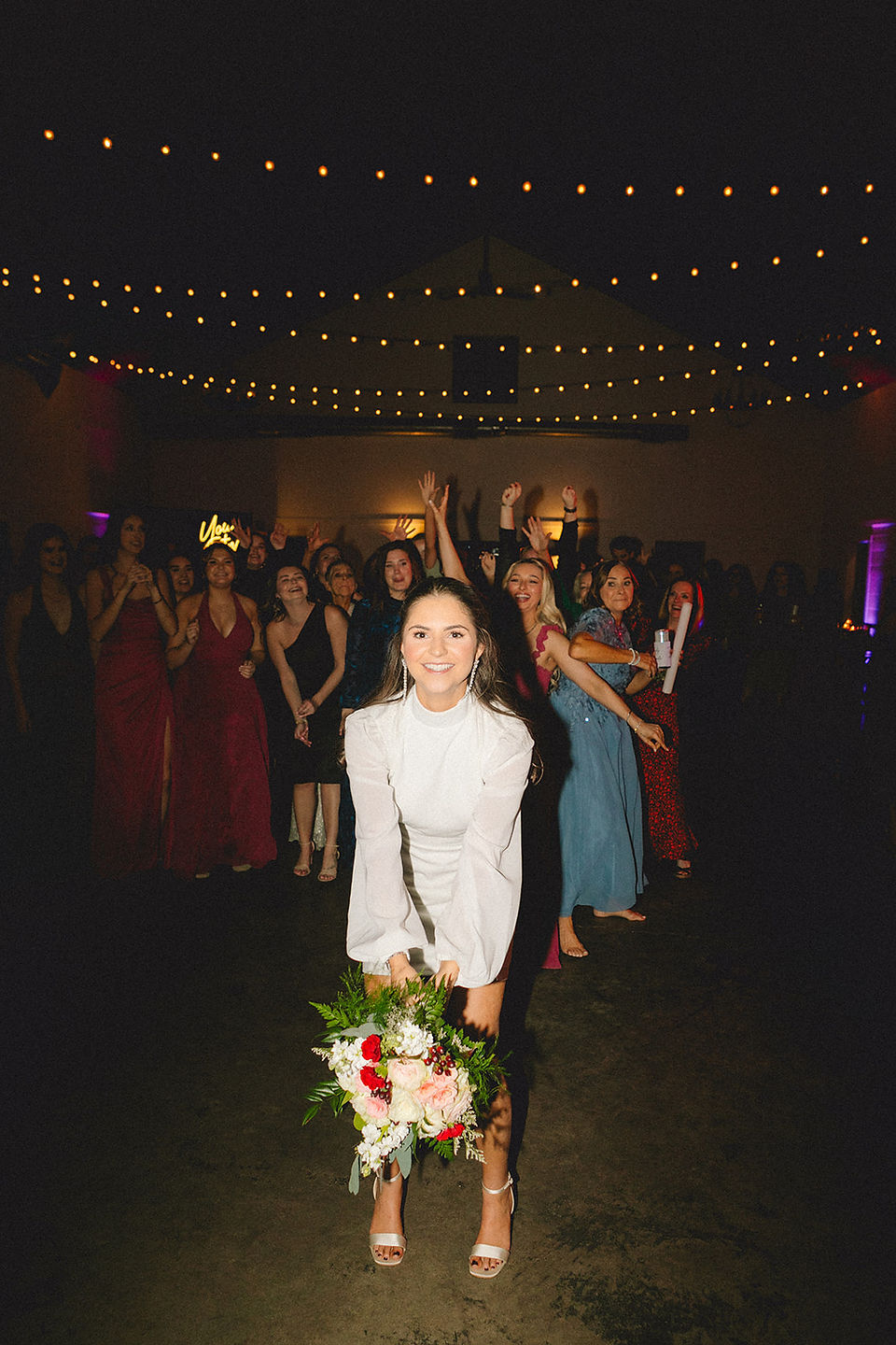 bride tossing bouquet at her wedding party photography