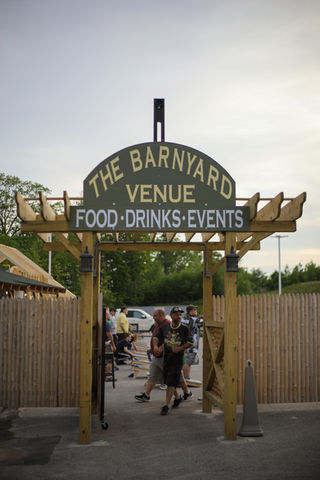Wooden gateway entrance to The Barnyard Venue reading “Food · Drinks · Events”