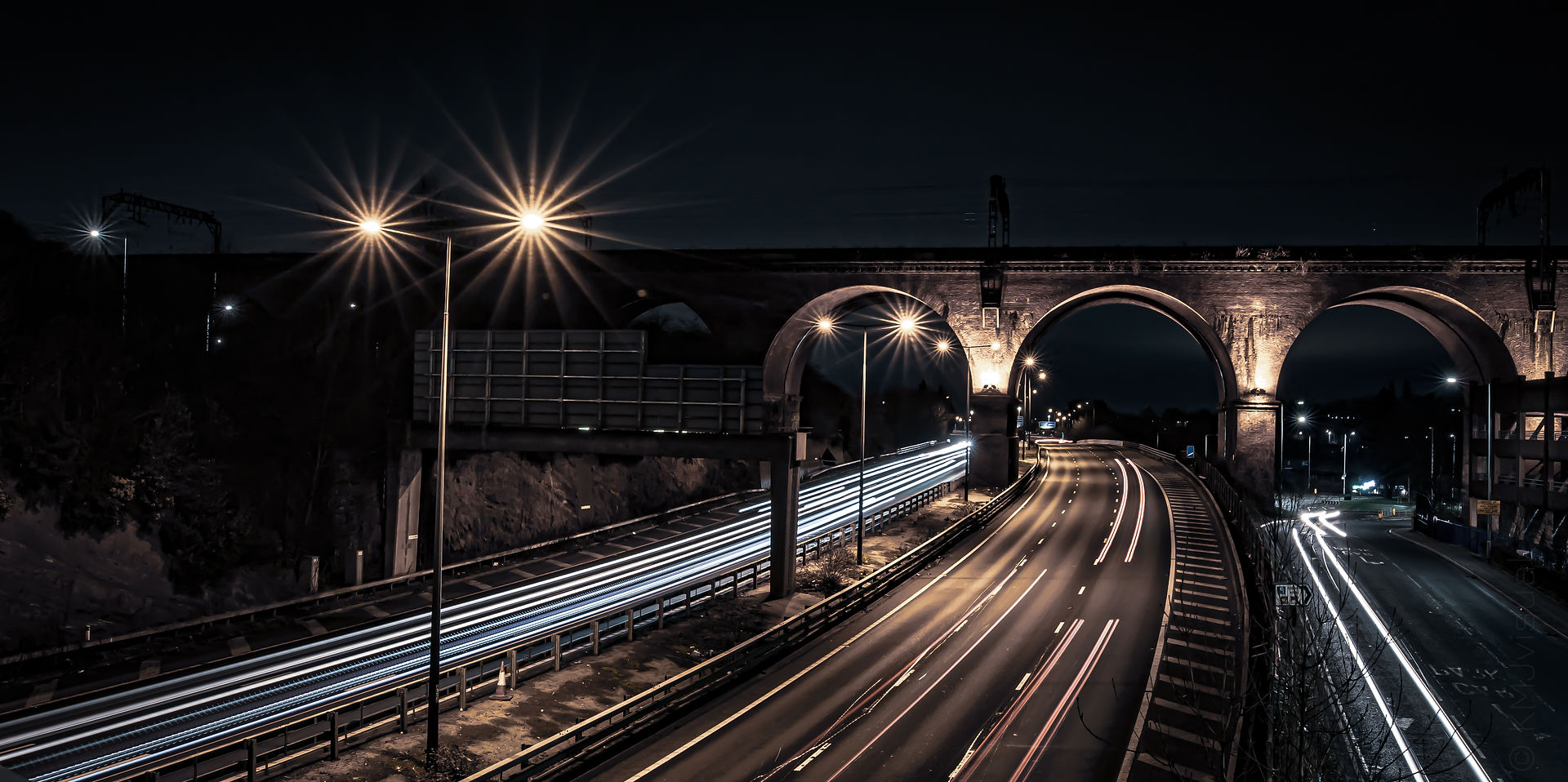 wide angle shot of Stockport Viaduct over motorway at night. cars creating light trails