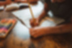 Child writing in a workbook with a pencil