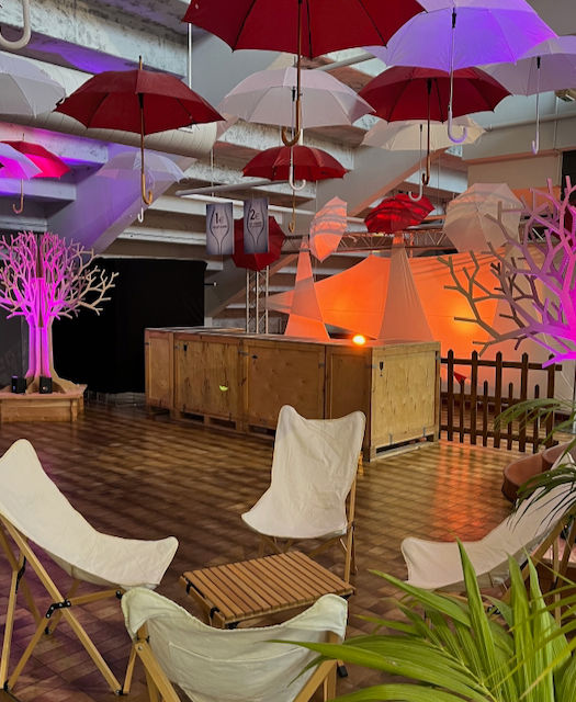 Arbres carton, fauteuils glamping, Box bar palette et parapluies au plafond. 