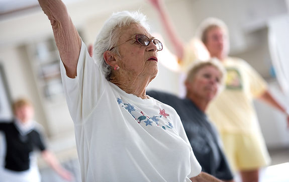 An elderly woman stretching in an exercise class