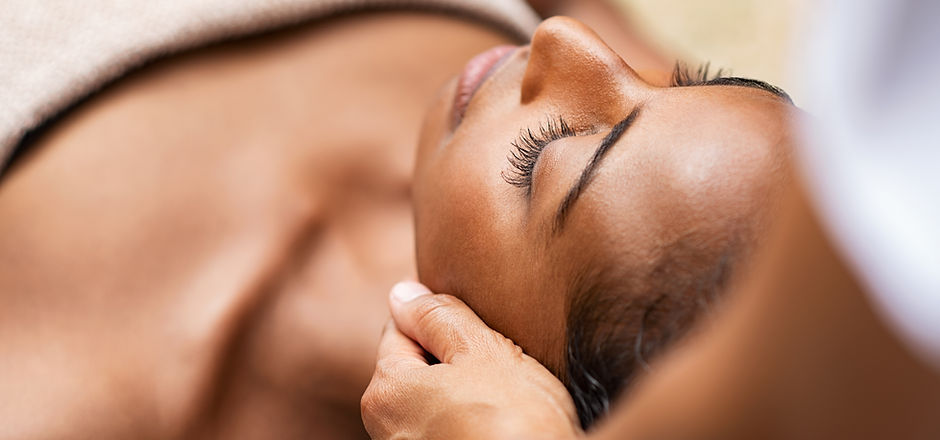 Beautiful african woman getting face massage in beauty spa. Black girl with closed eyes re